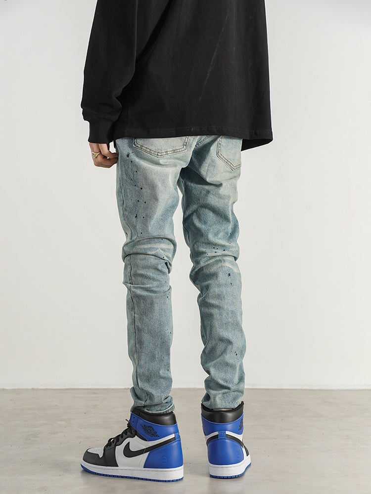 Kallistii painted effect slim fit jeans worn with black top and blue high top sneakers