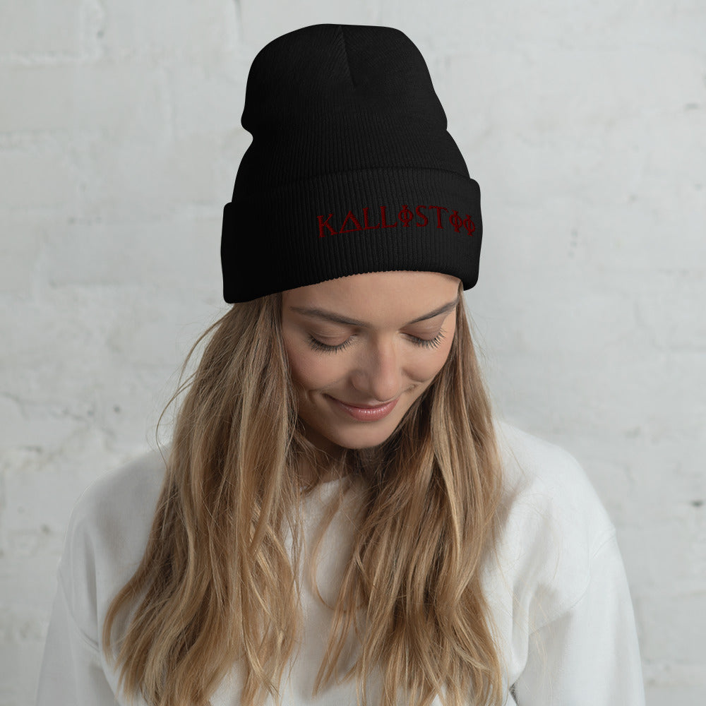 Black KALLISTII embroidered beanie with red stitching worn by woman with long blonde hair and white sweater