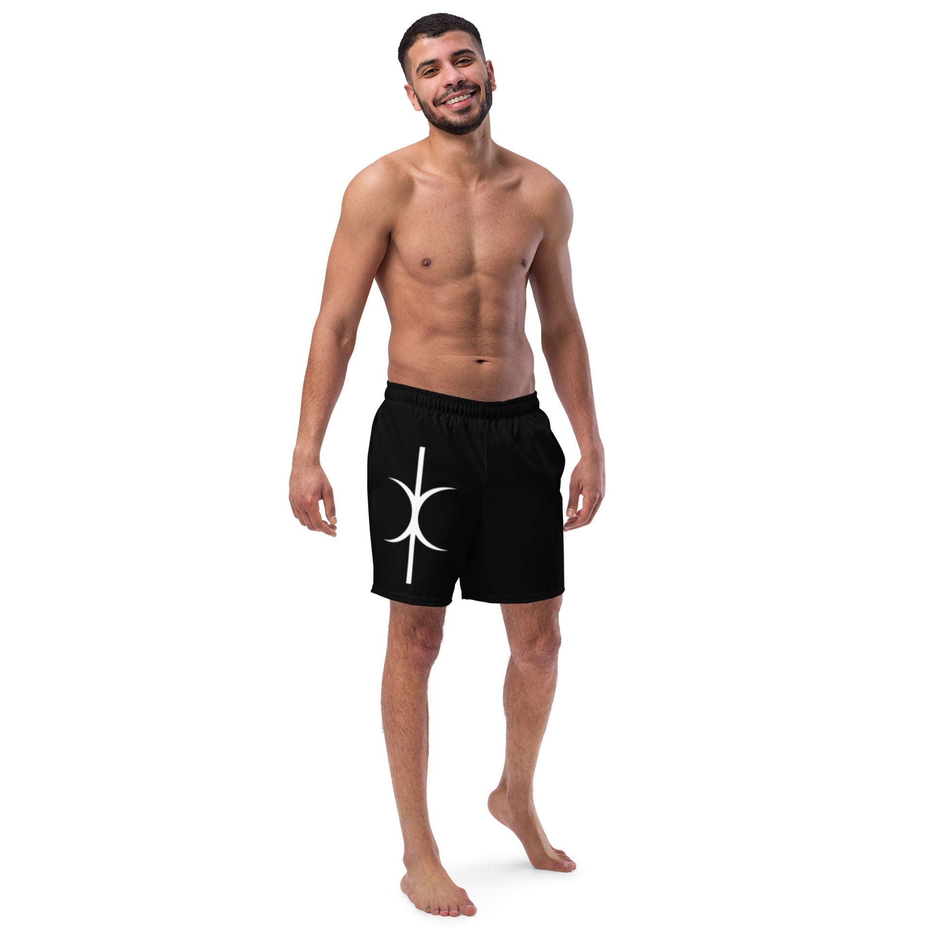 Man wearing black Hands of Eris swim trunks with white symbol design standing and smiling