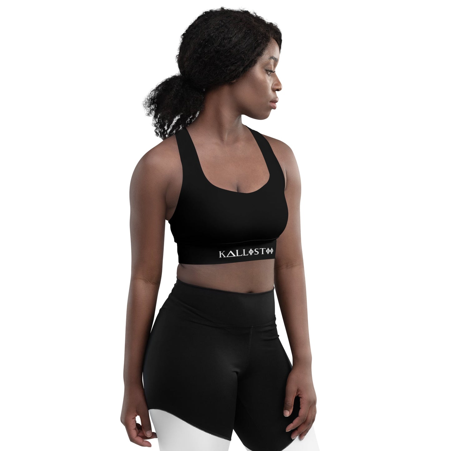 Woman wearing black KALLISTII activewear sports bra and black high-waisted leggings posing on white background