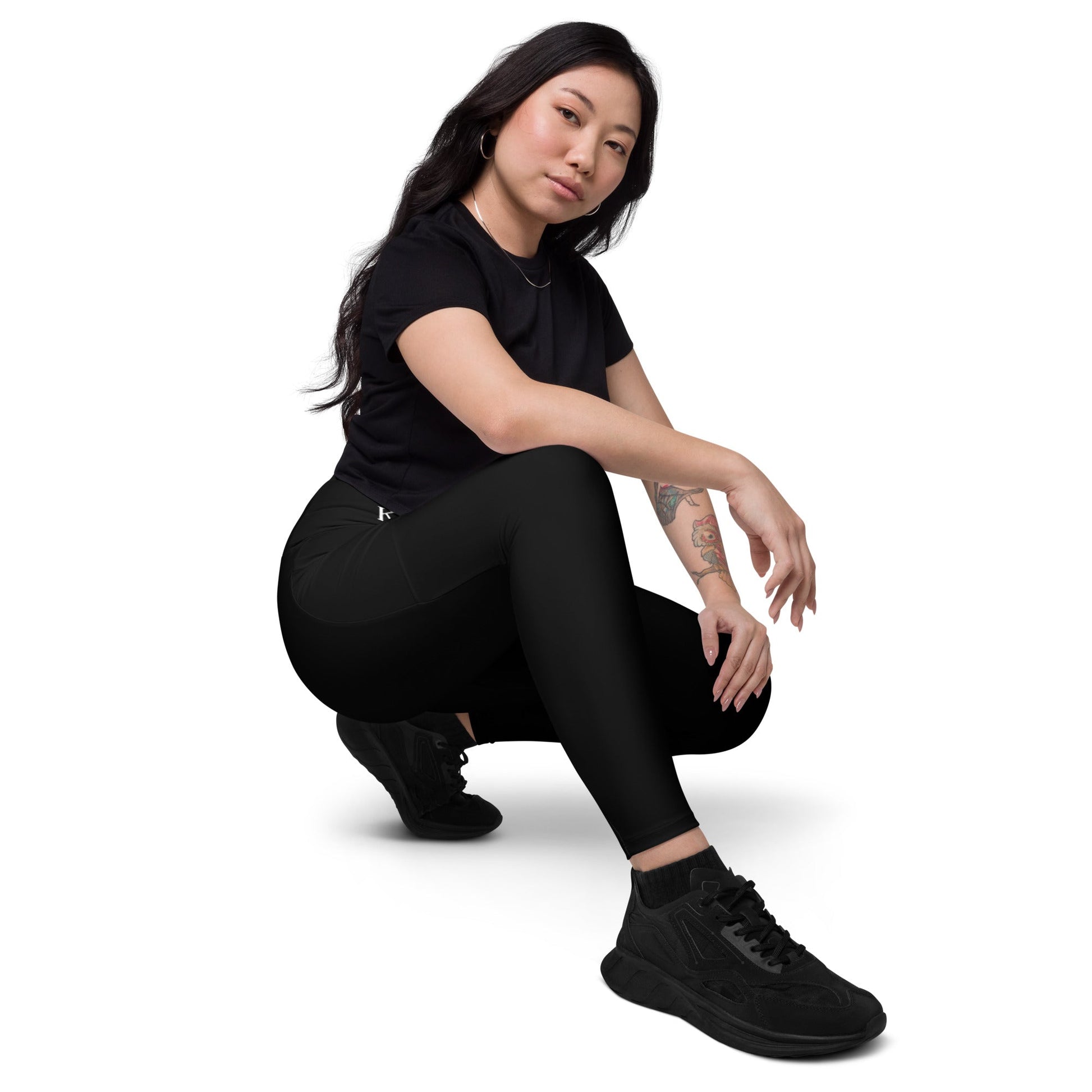 Woman wearing KALLISTII high waisted leggings in black paired with black sneakers and a black t-shirt