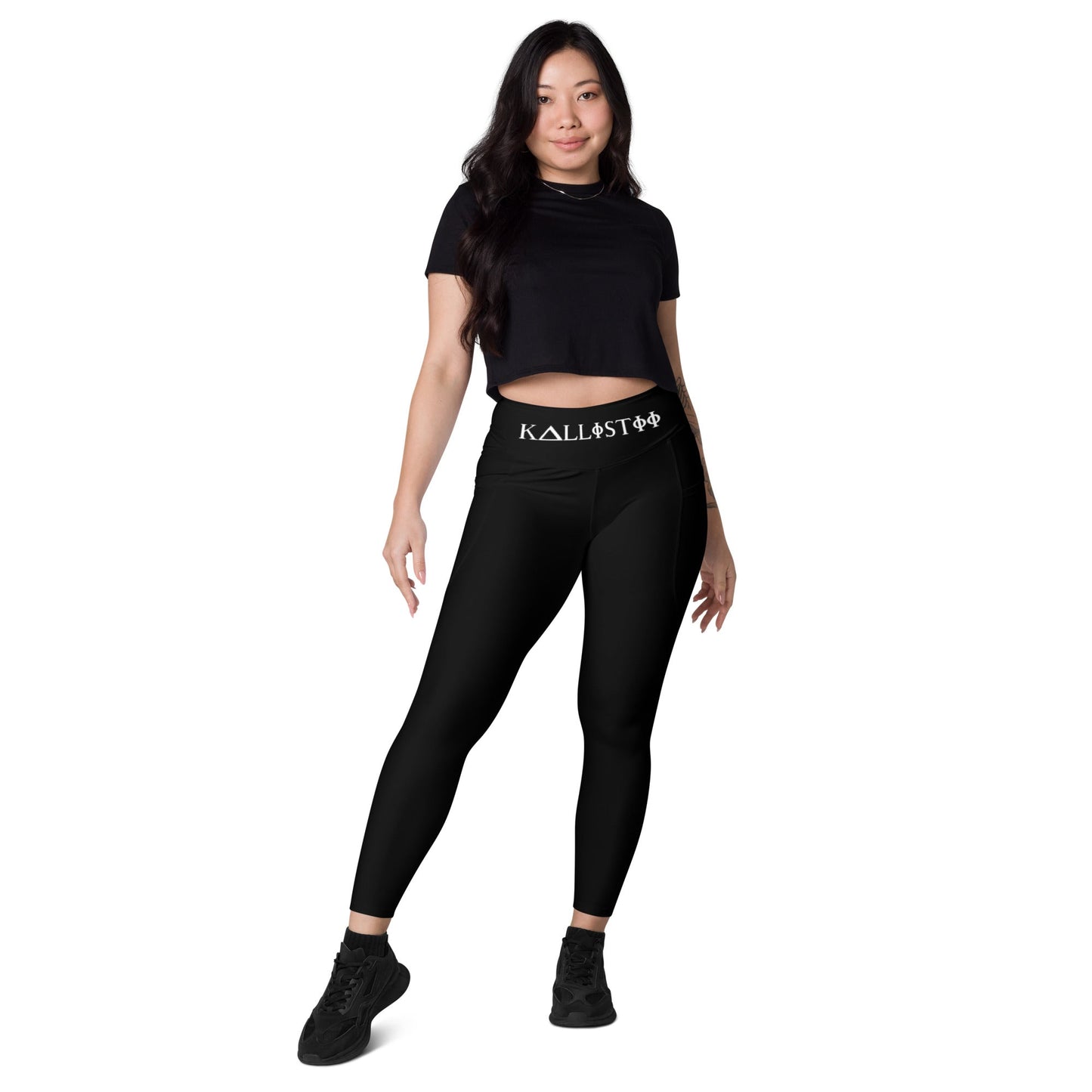 Woman wearing black KALLISTII high waisted leggings with logo waistband and black crop top