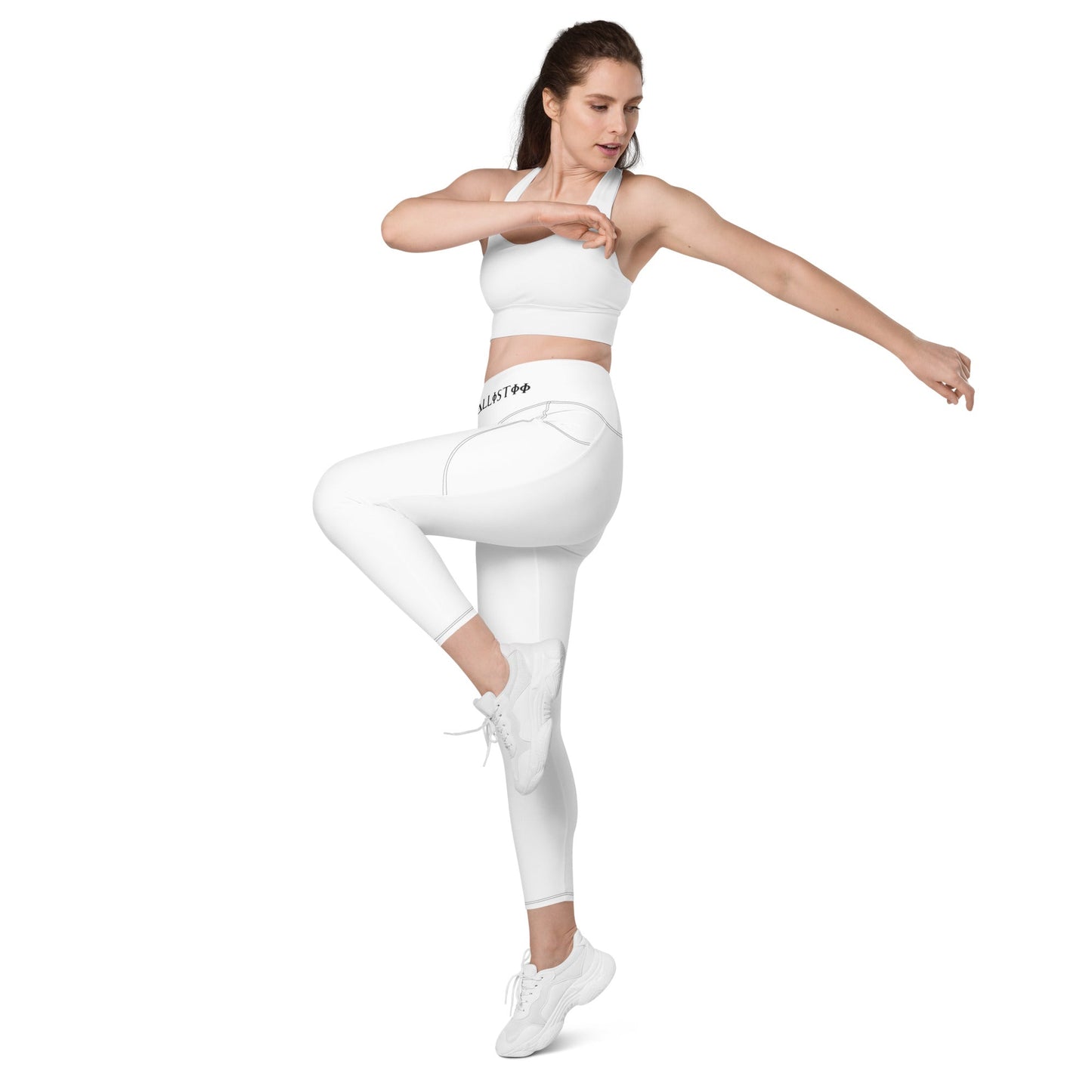 Woman wearing KALLISTII high waisted leggings in white performing a fitness pose with matching sports bra and white sneakers