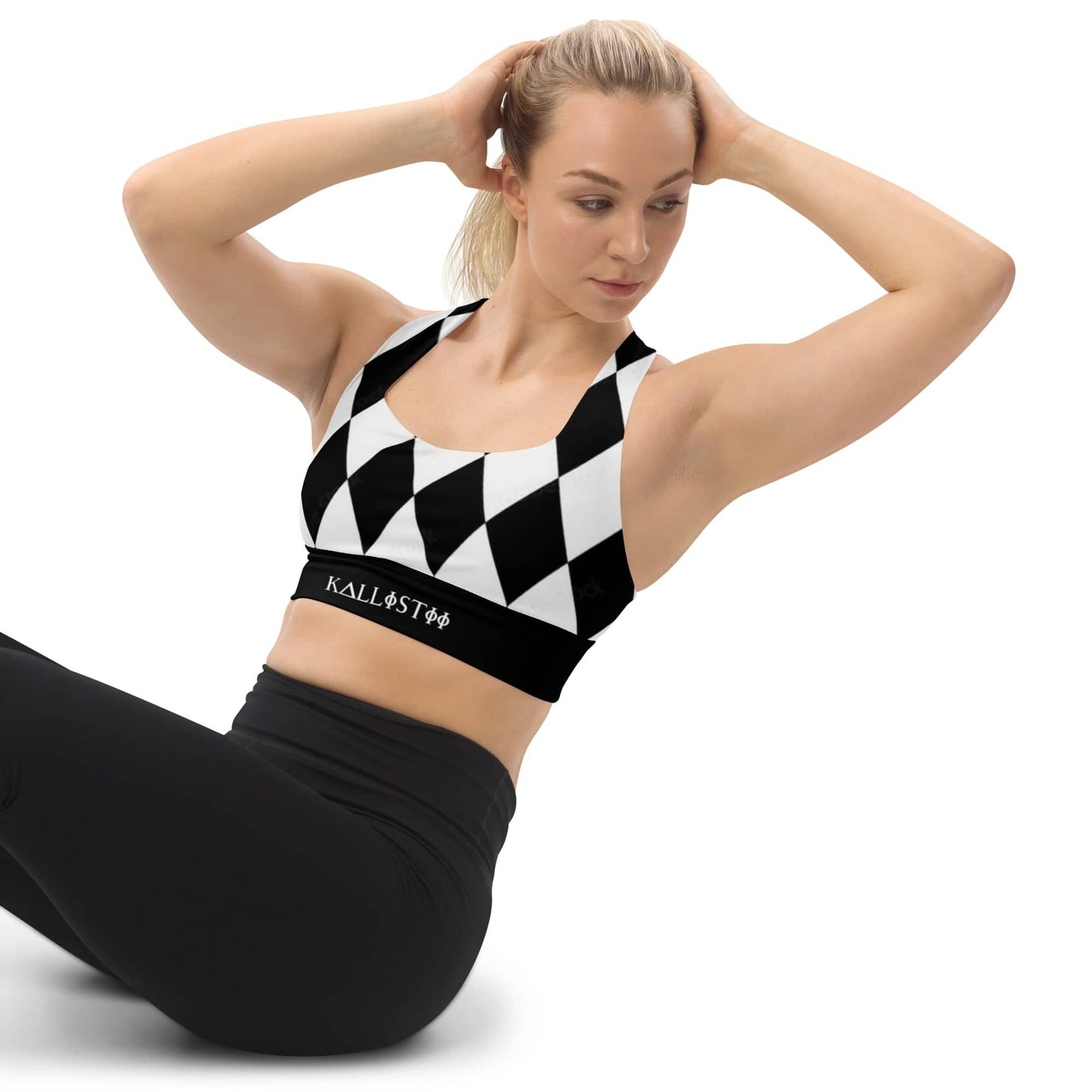 Woman wearing black and white harlequin sports bra by kallistii with black leggings in workout pose