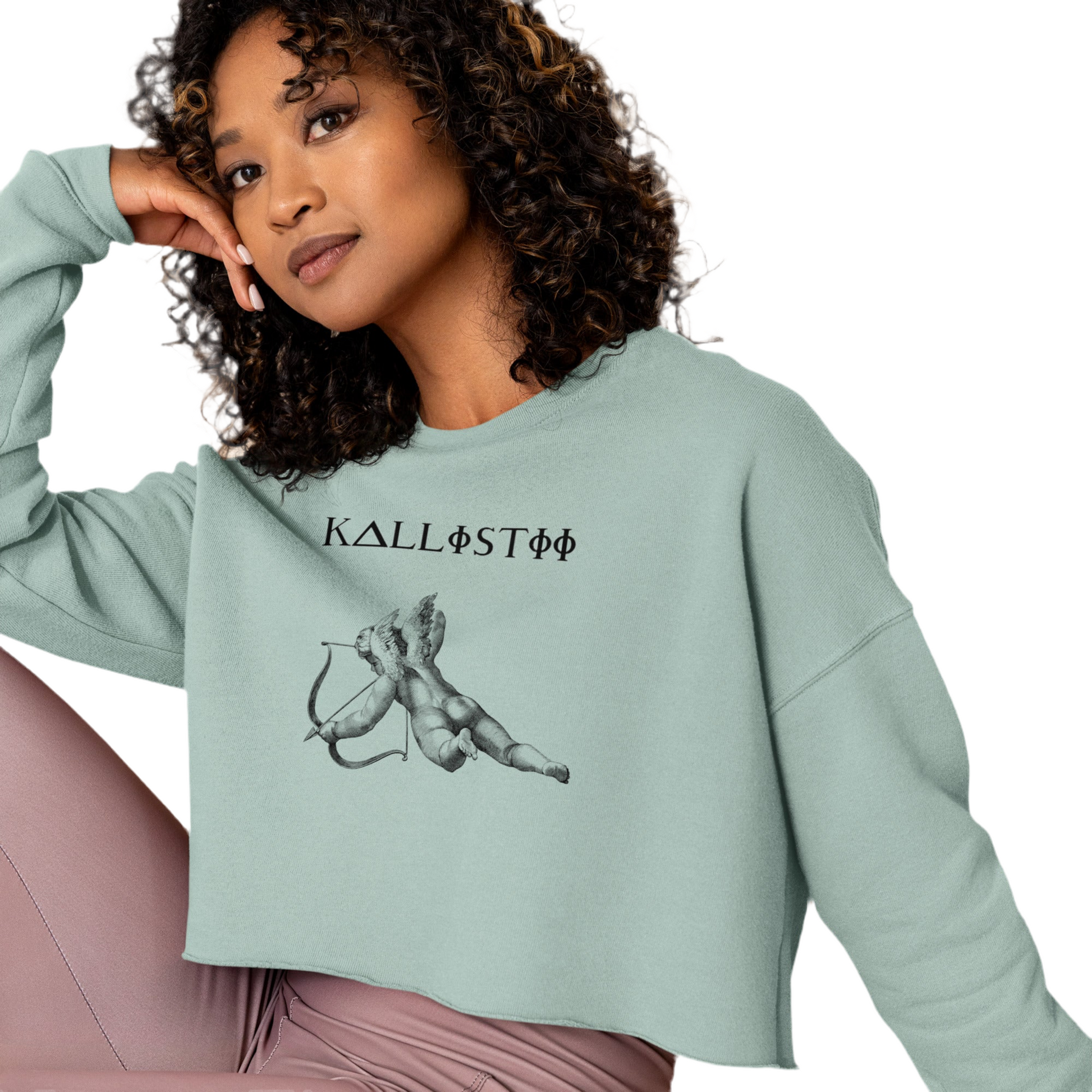 Kallistii Eros crop sweatshirt in light green with cupid graphic worn by woman with curly hair