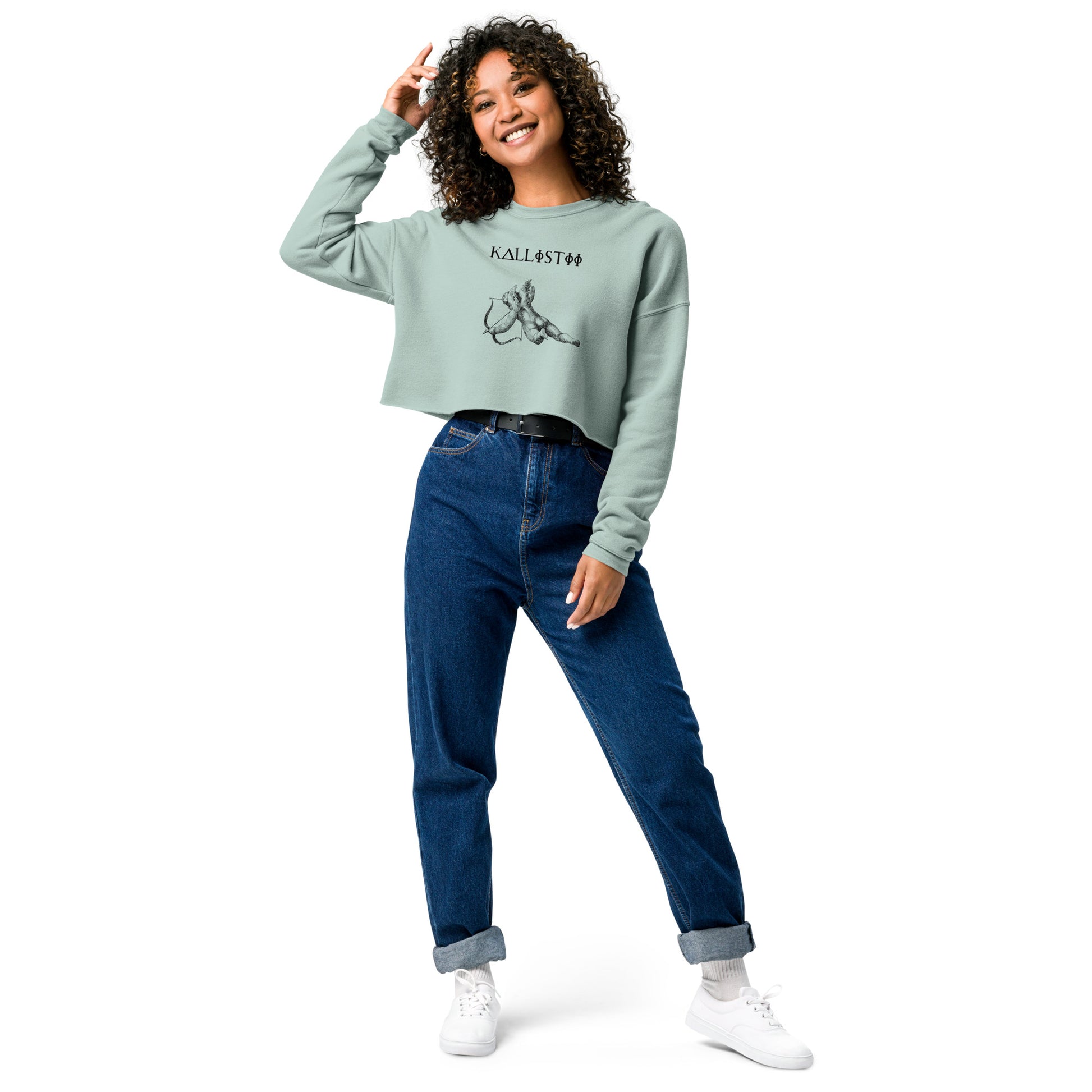 Woman wearing kallistii Eros crop sweatshirt in light green paired with high-waisted blue jeans and white sneakers