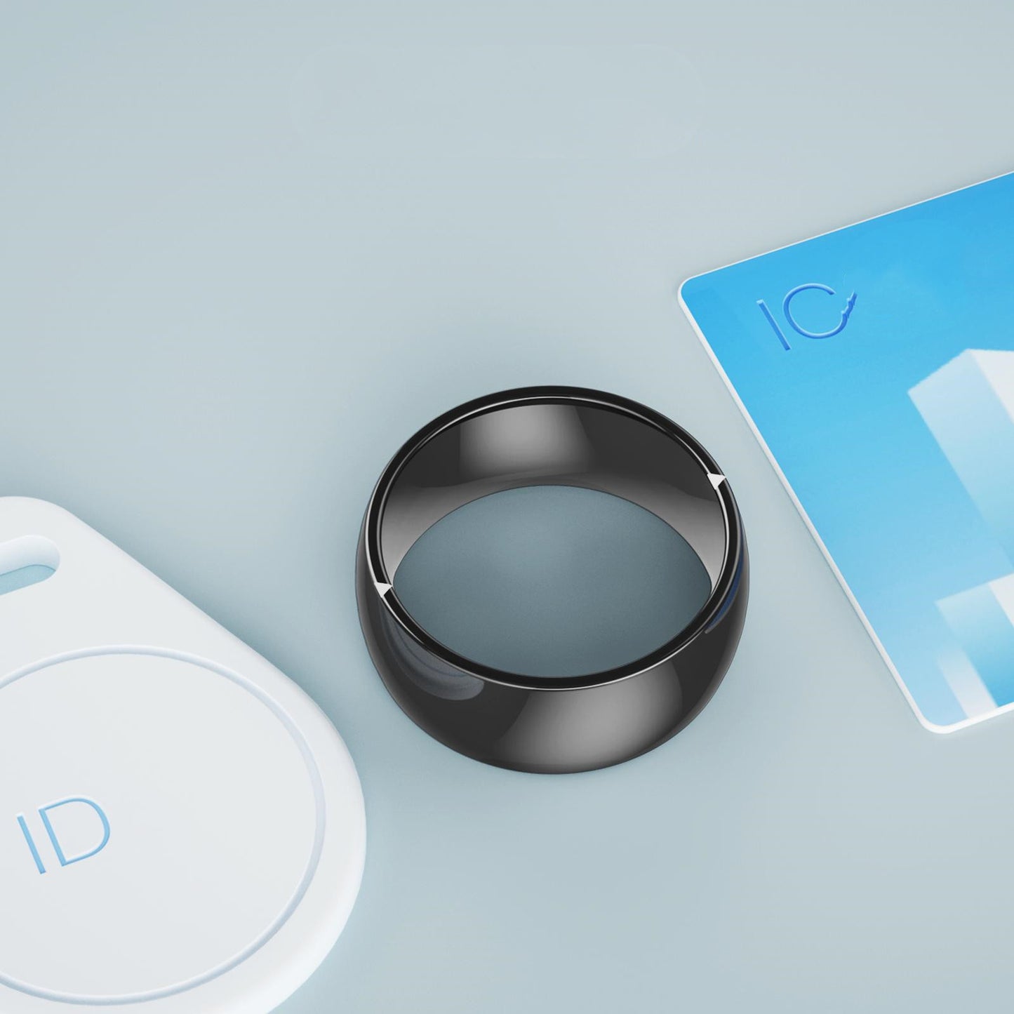 Black modern smart ring for tech lovers displayed on a light blue surface with ID and IC cards nearby