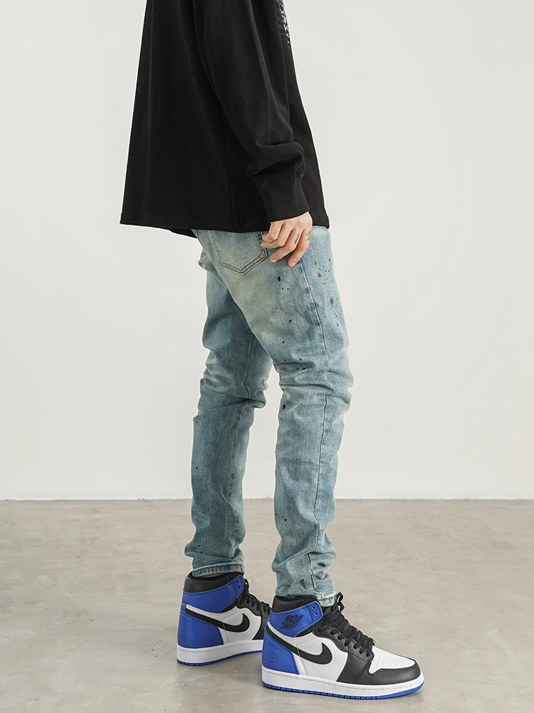 Kallistii painted effect slim fit jeans worn with black long sleeve shirt and blue white sneakers
