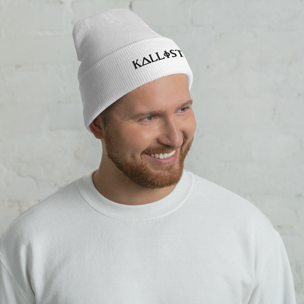 Smiling man wearing a white KALLISTII embroidered beanie with a white sweatshirt against a light background