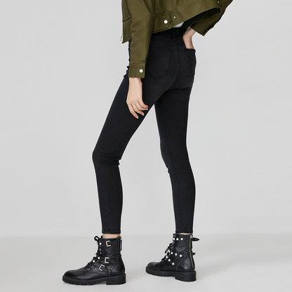 Woman wearing kallistii black fade skinny jeans paired with black studded combat boots and green jacket