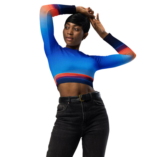 Woman wearing a kallistii skyline long-sleeve crop top with blue and orange gradient design paired with black high-waisted jeans