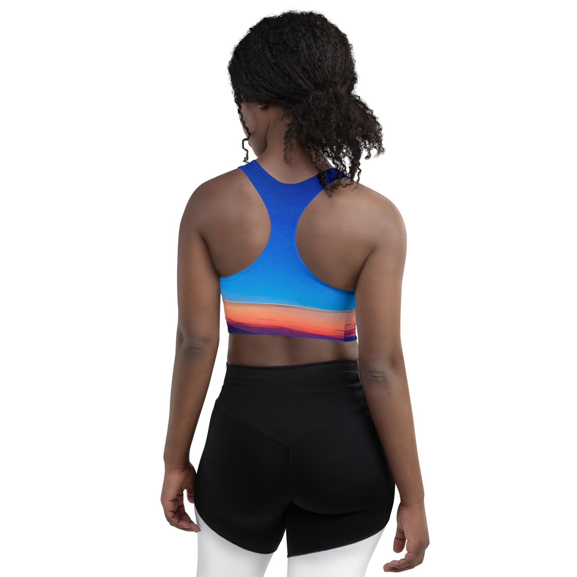 Back view of woman wearing kallistii skyline sports bra with blue and sunset gradient design