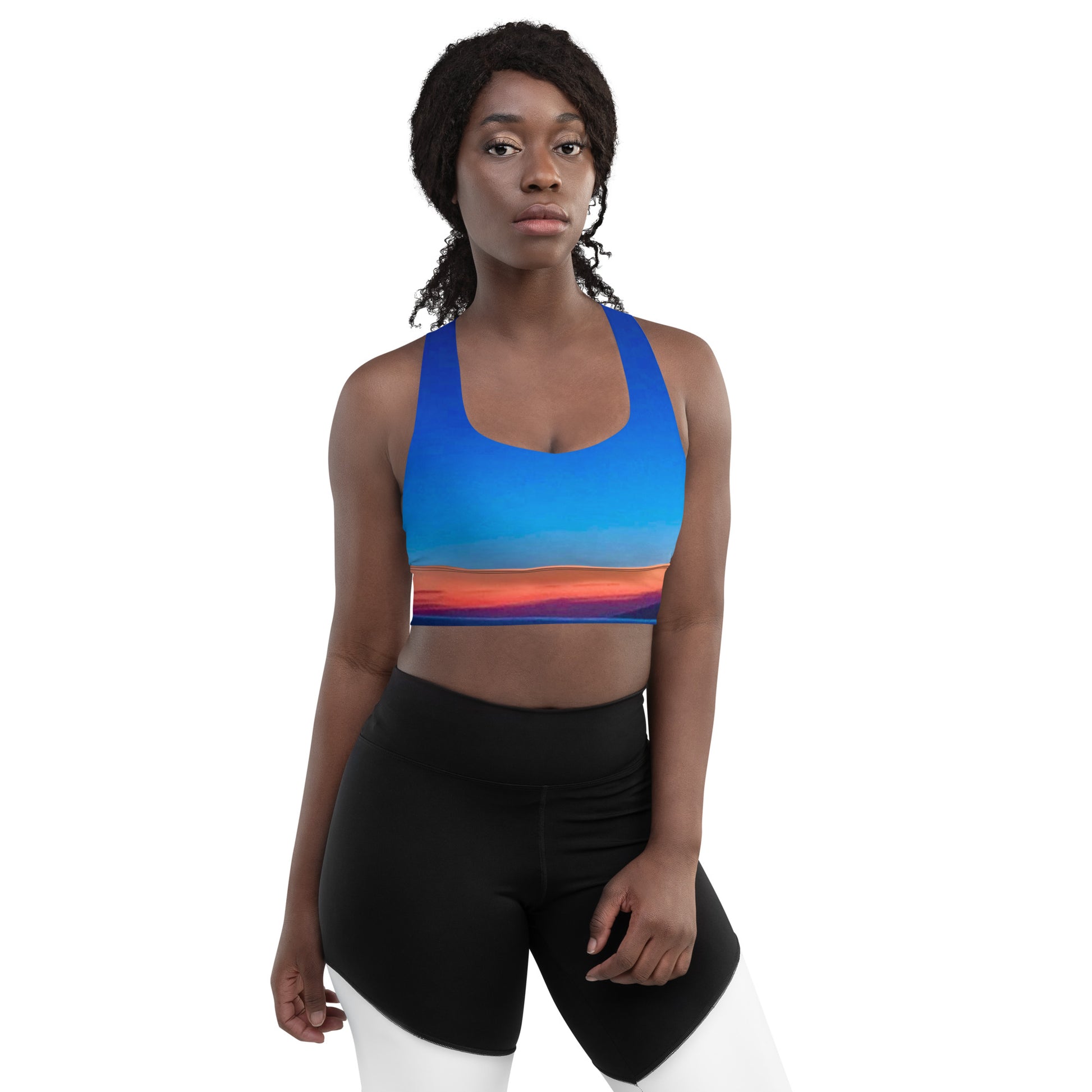Woman wearing kallistii skyline sports bra with blue and sunset design and black and white leggings