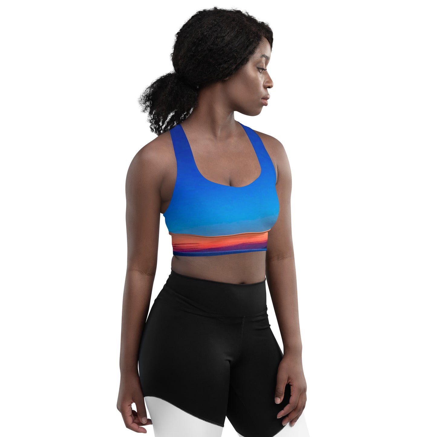 Woman wearing kallistii skyline sports bra in blue with orange gradient and black leggings